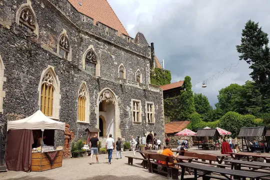 Kamienny zamek Grodziec z gotyckimi oknami, dziedziniec z kramami i ławami. Wiele osób zwiedza to miejsce, a opinie o zamku Grodziec są pozytywne.